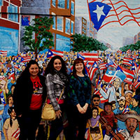 Students pose in front of a mural.