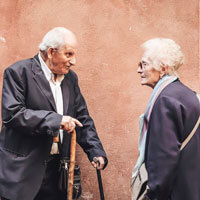 An elderly couple stand and talk.
