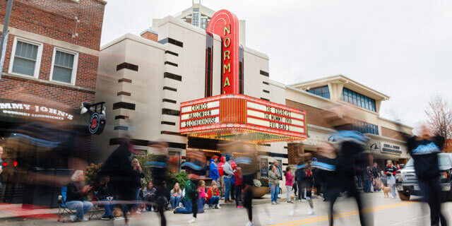 Street view of Normal Theater with people walking by and gathered outside.