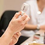 Female pulling medicine out of a vial into a syringe.