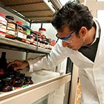 Male pharmacist reaching for a medication on a shelf.