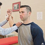 Male being assisted in stretches with his right arm.