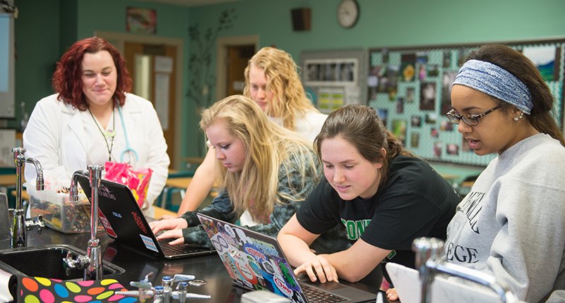 Four girls in a college of nursing lab looking at computers.