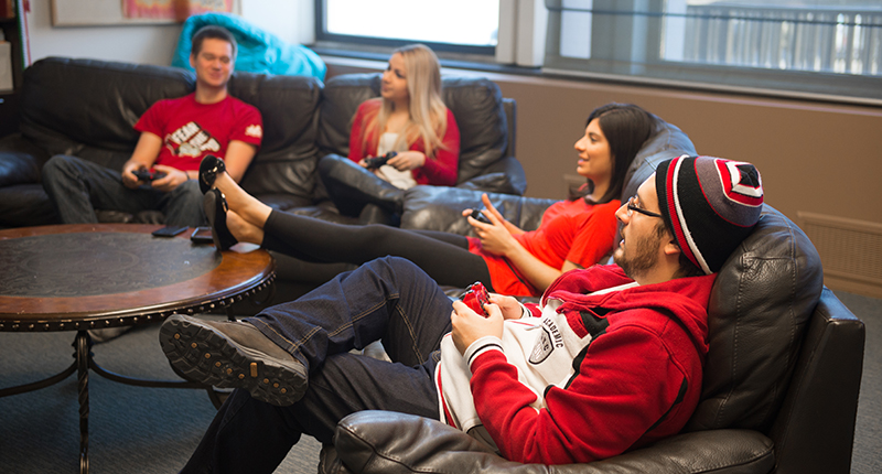 International students relaxing on a couch, playing video games.